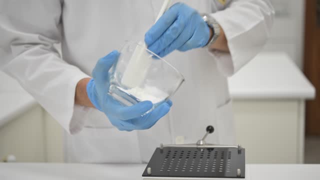 Crop pharmacist pouring medical powder into manual capsule filler