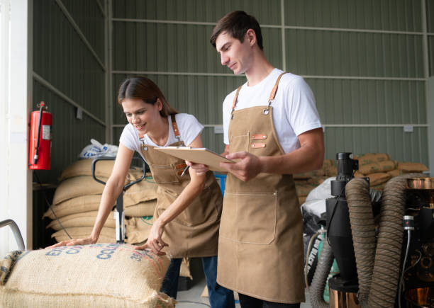 portrait of young female warehouse worker talking with male colleague in coffee beans warehouse - coffee bag green bean imagens e fotografias de stock