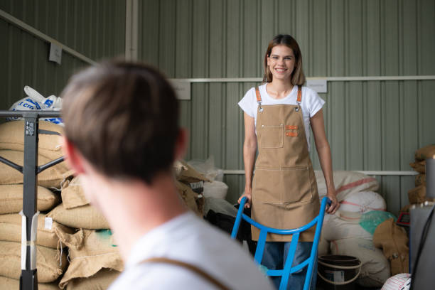 portrait of young female warehouse worker talking with male colleague in coffee beans warehouse - coffee bag green bean imagens e fotografias de stock