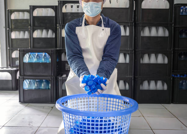 istock Blue plastic water bottle cap in hand worker or quality inspector in workwear in drink water factory.drinking water business 1528184238