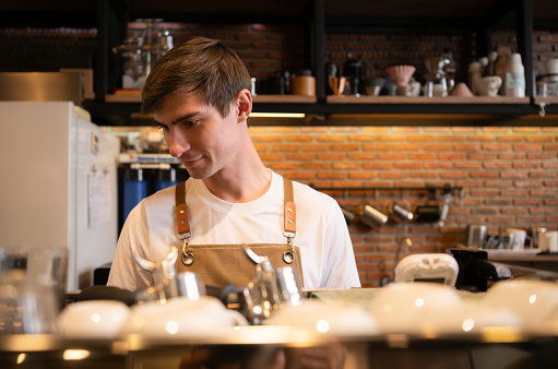 Portrait of a young male barista preparing coffee in a coffee shop