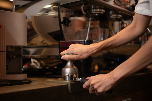 Close-up of barista hands using Portafilter for making espresso.
