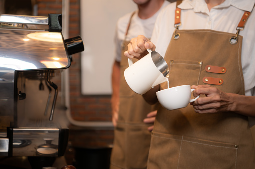 Barista pouring coffee into a cup in coffee shop, closeup