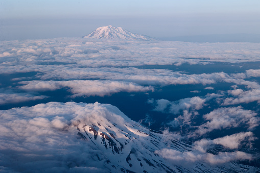 Aerial view of Mount Saint Helens partially obscured by clouds with Mount Adams in the background. Both mountains are stratovolcanos of the Cascade Range in Washington.