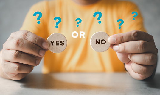 Man holding two wooden blocks with yes or no written on them, making the decision concept.