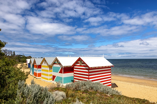 Brighton beach Victorian bathing boxes. Brightly painted colourful beach huts line the sand in Melbourne, Australia. They are highly desirable and extremely expensive real estate.