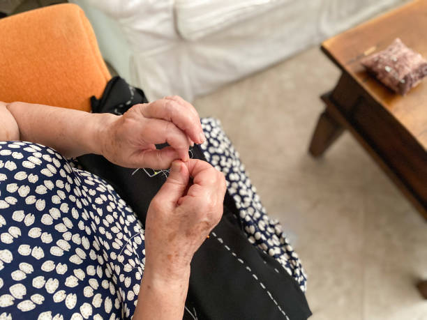 istock Old woman’s hands sewing a black shirt 1528308490