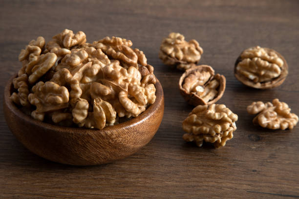 istock Peeled walnuts and whole walnuts wooden table,overhead view 1528329425