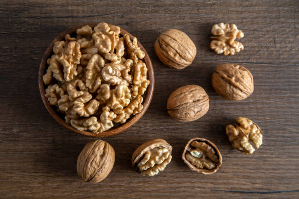 istock Peeled walnuts and whole walnuts wooden table,overhead view 1528357757