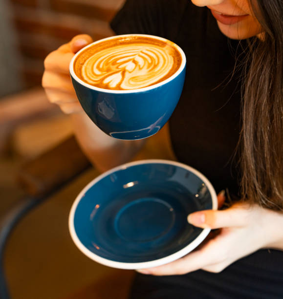une femme boit du café chaud préparé en forme de motif - coffee coffee cup love cappuccino photos et images de collection