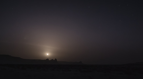 Chalk and limestone remnants in the Kazakh steppe at night against the background of the starry sky and the moon, vertical landforms after weathering in the desert