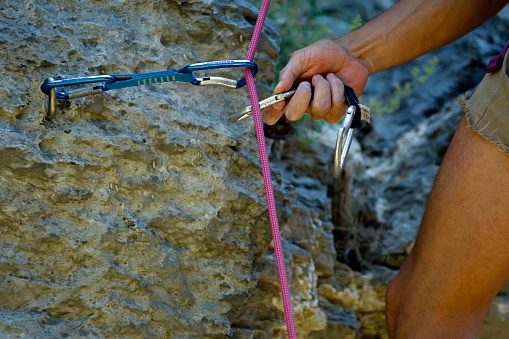 Close up shot of a rock climbing assisted belaying device and a green rope.