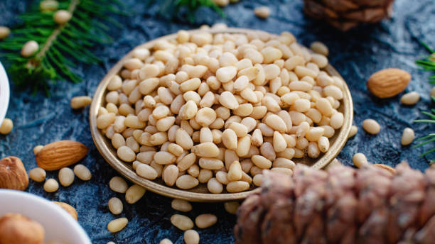 istock Peeled pine nuts lie in plate among cones. Still life of pine nut kernel. 1528455587