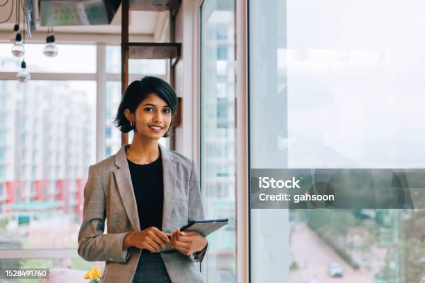 Young Businesswoman Posing By Window Stock Photo - Download Image Now - Businesswoman, Expertise, Indian Ethnicity