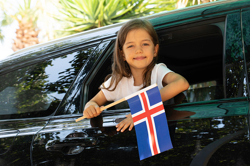 Girl holding Iceland flag in the car.
