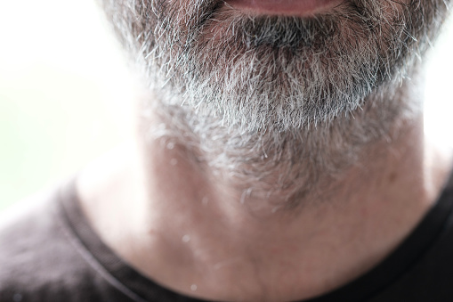 Grey beard of unrecognizable mature male. We don't see his face and most of the images is out of focus. Getting old and healthy concept.