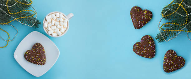 istock Hot chocolate with marshmallows in the white cup and Christmas heart shaped gingerbread on the blue background. Copy space. 1528541193