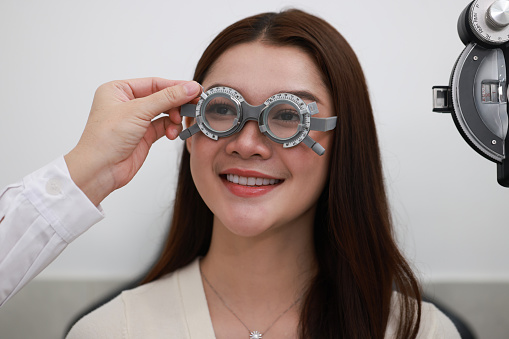 The attractive woman with an optometrist trial frame. female patient to check vision in an ophthalmological clinic