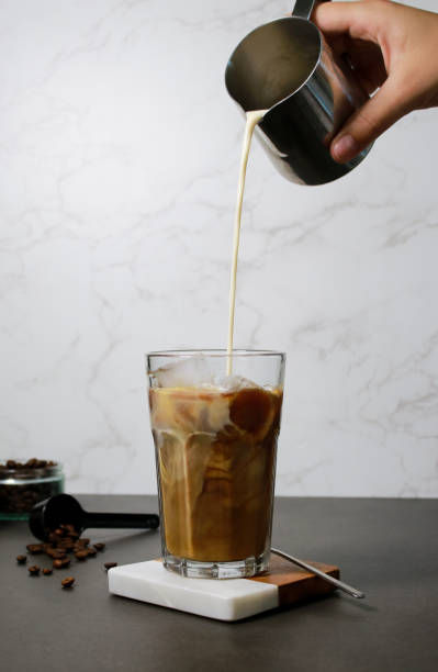 istock Pouring oat milk into cold ice coffee in a tall glass 1528666861