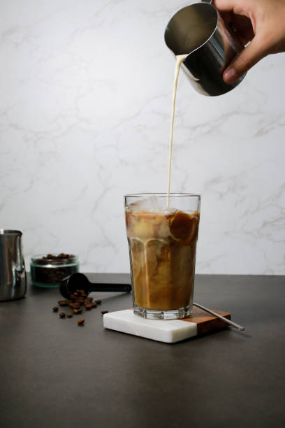 istock Pouring oat milk into cold ice coffee in a tall glass 1528666964
