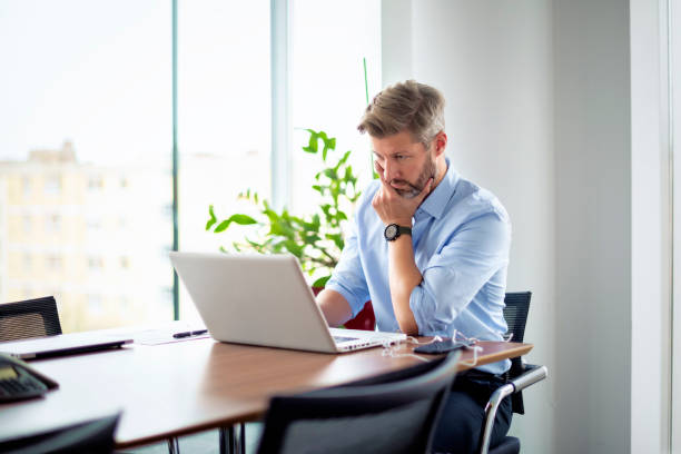 istock Mid aged businessman sitting at office and using laptop for work 1528722636