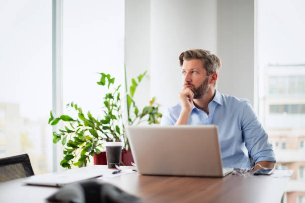 istock Stressed businessman sitting at office desk and using laptop for work 1528722642