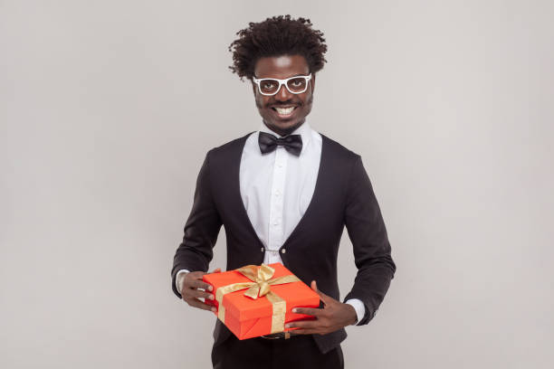 istock Smiling satisfied man in glasses standing holding present box looking at camera with toothy smile. 1528728365