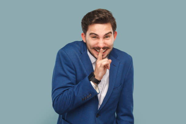 istock Funny smiling man with mustache standing with finger near lips, showing shh gesture, keeps secret. 1528736373