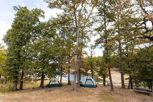 Camping tents near a beautiful lake among trees, campsite, adventure vacation concept, Broken bow lake in Oklahoma, USA.