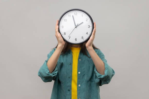 istock Unknown woman holding wall clock hiding her face, time management, schedule and meeting appointment. 1528751647