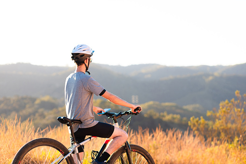 Man standing with his mountain bike to rest while contemplating the mountain landscape in the background.