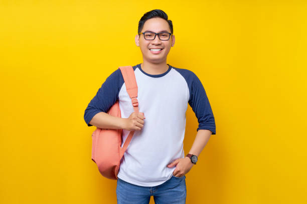 istock Smiling attractive young Asian man student wearing casual clothes standing confident while looking at the camera isolated on yellow background. Education in high school university college concept 1529021138