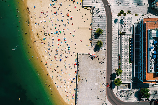 Top down drone view of Ribeira Beach in Cascais, Portugal on a summer day with many people on the beach