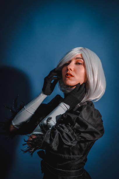 portrait de femme cosplayeuse en costume noir et perruque blanche en studio sur fond bleu - manga style fantasy cartoon full length photos et images de collection