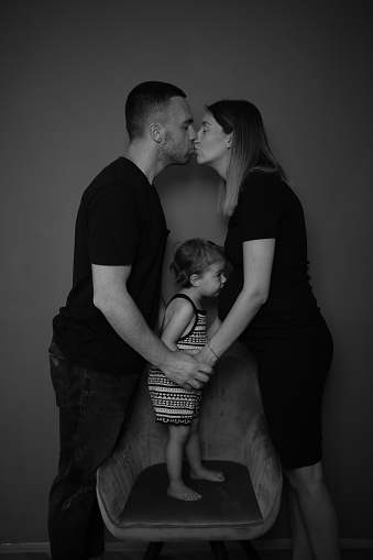 Portrait of a young father posing with his adorable daughter and his pregnant wife in an advanced state of pregnancy.