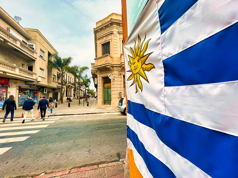 montevideo, uruguay - October 30 2022: the uruguay flag with sunshine hanging in the ciudad vieja and people walking on the main shopping street