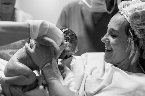 Mother holding her newborn baby child after labor in a hospital. Mother giving birth to a baby boy. Parent and infant first moments of bonding. Buenos Aires. Argentina