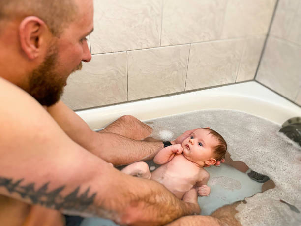 istock Father tenderly holds newborn baby in bath for first time 1529330301