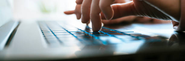 Low angle closeup view of female hands typing on laptop computer keyboard