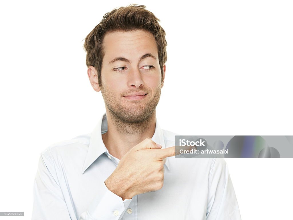 Man pointing Young man pointing a bit sneaky looking at copy space. Handsome young Caucasian businessman isolated on white background. See more: Men Stock Photo