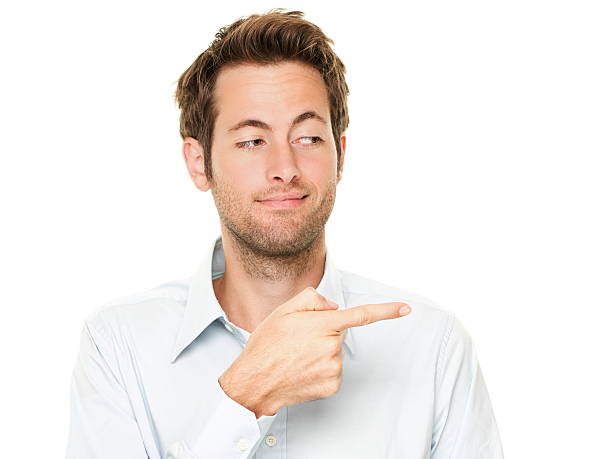 Man pointing Young man pointing a bit sneaky looking at copy space. Handsome young Caucasian businessman isolated on white background. See more: sideways glance stock pictures, royalty-free photos & images