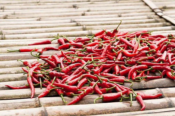 small pile of red hot chillies on a bamboo platform.