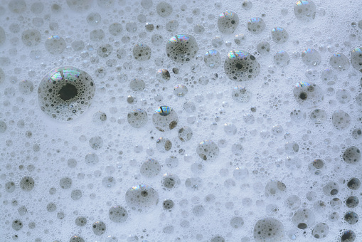 A close-up view of bubbles on yellow washing liquid, creating a bubbly background.