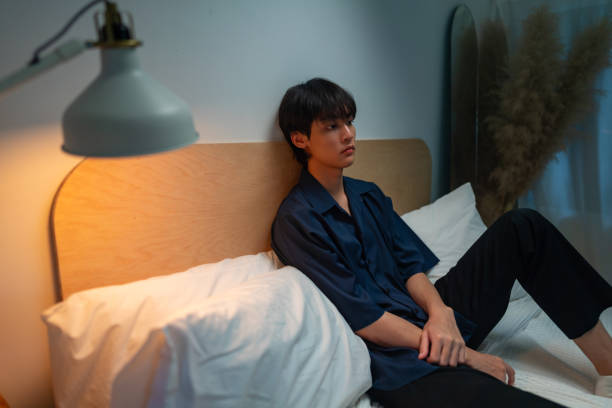 istock Depressed Asian man sitting on the bed. 1529388396