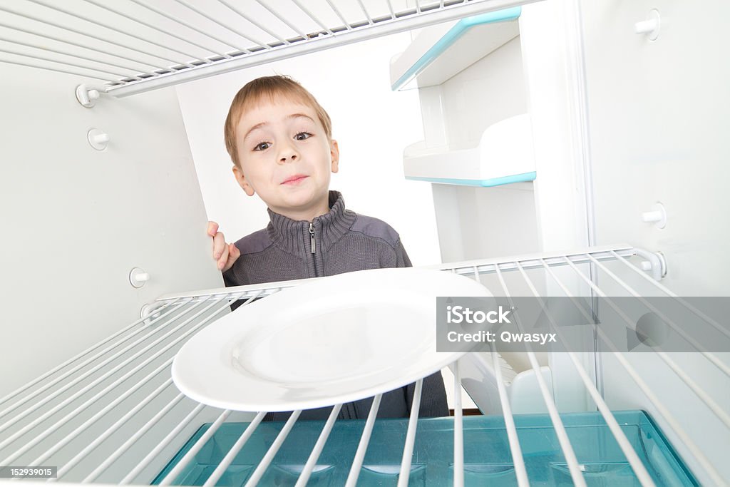 Boy and Empty Refrigerator Boy looking into empty refrigerator. Appliance Stock Photo