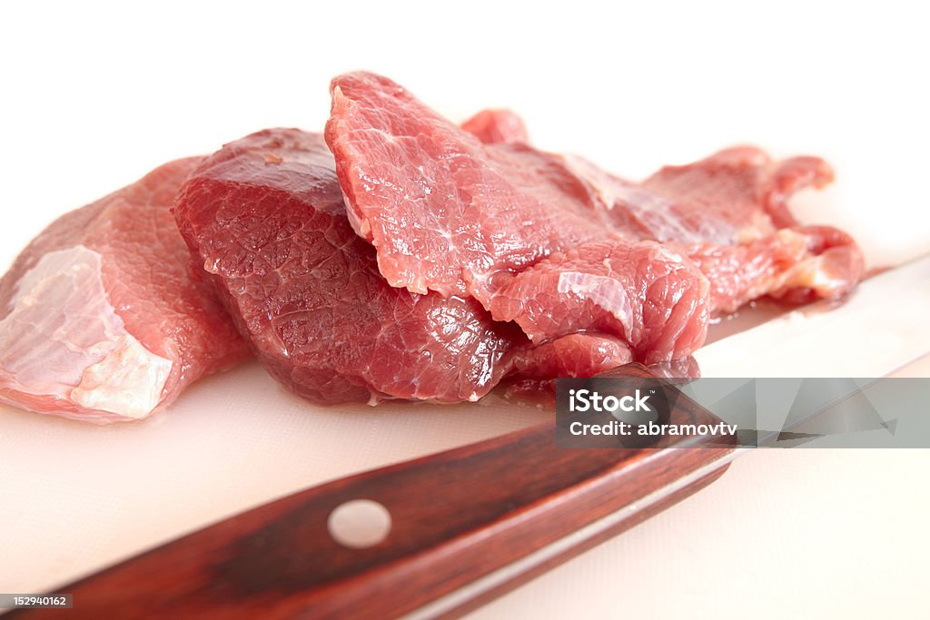 Fatias de carne e nítidas faca no branco tábua de corte - Foto de stock de Adaga royalty-free