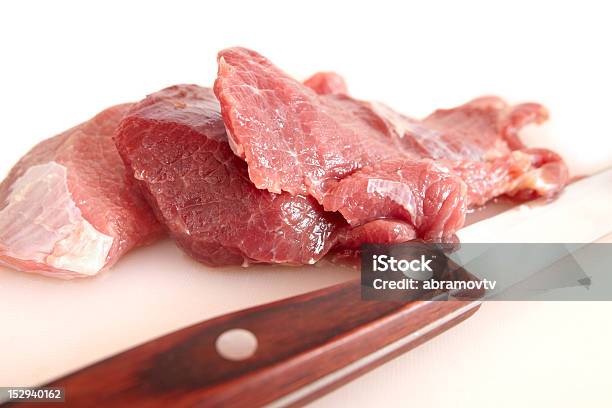 Foto de Fatias De Carne E Nítidas Faca No Branco Tábua De Corte e mais fotos de stock de Adaga