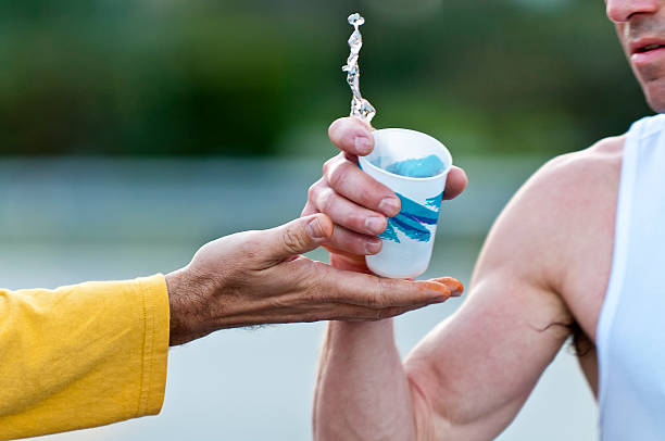 Runner grabbing water during a marathon from a volunteer hand. Use of selective focus.
