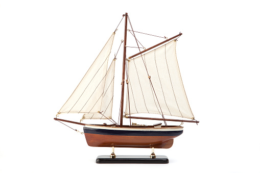 Model of a wooden sailboat with white sails