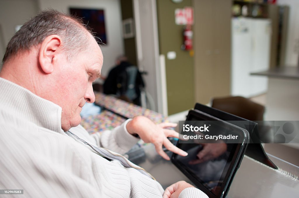 Mature homme âgé avec un handicap de l'ordinateur à écran tactile de l'exploitation - Photo de Adulte libre de droits